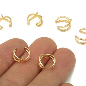 May include: Gold-colored ear cuffs in various designs. The image shows several ear cuffs, some with a simple curved design and others with multiple layers. The ear cuffs are displayed against a white background.