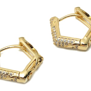 May include: A pair of gold hoop earrings with a geometric design and clear cubic zirconia stones.