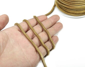 May include: Gold chain with a snake-like design. The chain is coiled on a hand and a spool.