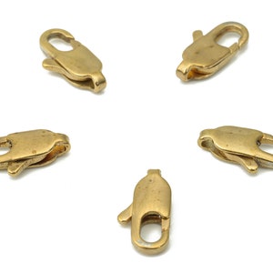 Puede incluir: Cinco cierres de langosta de metal dorado, comúnmente utilizados para la fabricación de joyas.