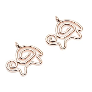 May include: Two rose gold turtle charms with a swirl design. The charms are made of metal and have a shiny finish.