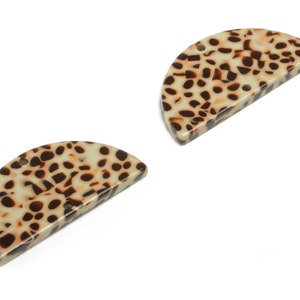 Może przedstawiać: Dwa półkoliste spinki do włosów z żywicy z brązowym i kremowym wzorem lamparta.