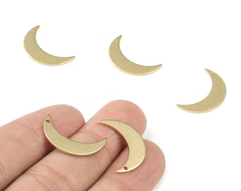 May include: Several gold-colored crescent moon charms. The charms are made of metal and have a smooth, matte finish. Each charm has a small hole at the top for stringing. The charms are scattered on a white background.