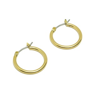 Può includere: Un paio di orecchini a cerchio dorati. Gli orecchini sono semplici e classici, con una finitura liscia e lucida.