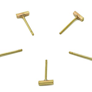 May include: Five gold bar stud earrings. Each earring features a small, rectangular bar with a post for piercing.