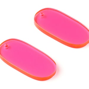 以下が含まれることがあります： 鮮やかなオレンジ色の縁取りが付いた、明るいピンク色の楕円形アクリルイヤリングパーツが2つ。各パーツの上部には、イヤリングフックを取り付けるための小さな穴があります。白い背景に表示されています。