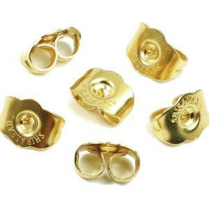 Peut inclure: Six dos d'oreille dorés. Les dos sont en forme de croissant de lune avec un petit trou au centre. Les dos sont estampillés des mots "SHIRALEE" et "MADE IN USA".