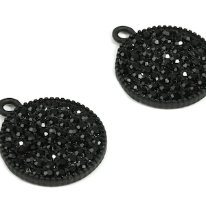 May include: Two black metal charms with a round shape and a black rhinestone design.