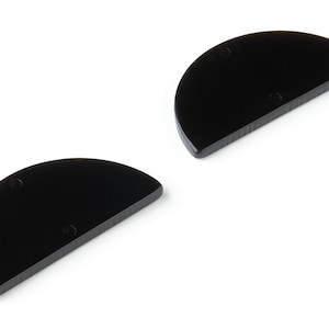 Puede incluir: Dos piezas de madera de forma semicircular negra. Cada pieza tiene dos pequeños agujeros.