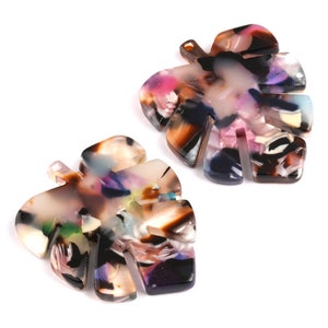May include: Two colourful, multi-coloured, plastic, leaf-shaped charms. The leaves are brown, pink, purple, and green.
