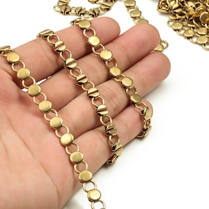 Puede incluir: Cadena dorada con eslabones redondos y acabado texturizado. La cadena se muestra en una mano, con varios hilos de la cadena.