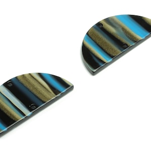 Może przedstawiać: Dwa półokrągłe guziki z żywicy z czarno-niebiesko-złotym paskowanym wzorem. Guziki mają po dwa otwory.