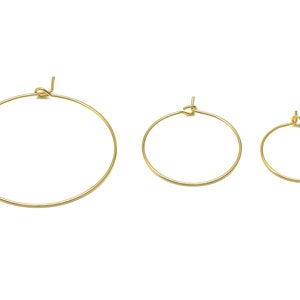 Pode incluir: Três brincos de argola dourados de diferentes tamanhos. A argola maior tem um diâmetro de aproximadamente 5 cm, a argola média tem um diâmetro de aproximadamente 4 cm e a argola menor tem um diâmetro de aproximadamente 2,5 cm.