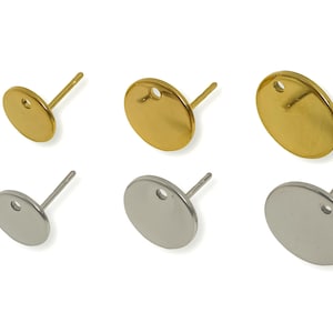 May include: Six earring posts with flat, round pads. Three are gold-coloured, and three are silver-coloured. Each post has a small hole in the pad for attaching jewellery findings. The posts are arranged on a white background.