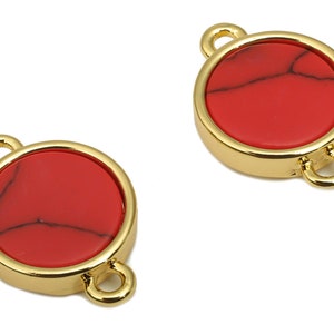 May include: Two gold-toned metal circle charms with red stone inlays. Each charm has two loops for attaching to jewellery.