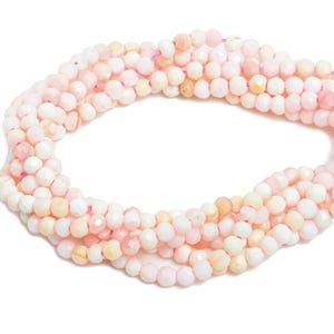 May include: A strand of pink and white faceted gemstone beads. The beads are small and round, and they are strung on a clear thread.
