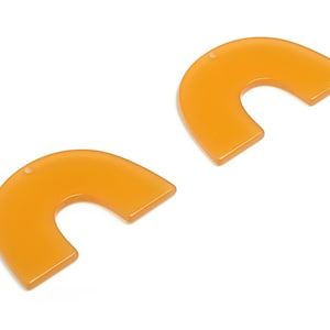 May include: Two orange acrylic half-circle shapes with a hole at the top. These shapes are perfect for crafting projects.
