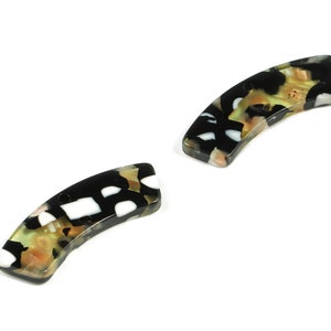 Puede incluir: Dos cuentas curvas y rectangulares con un patrón de carey. Las cuentas presentan una mezcla de colores negro, blanco, beige y melocotón. Las cuentas son ligeramente arqueadas y tienen un acabado brillante, perfectas para bisutería.