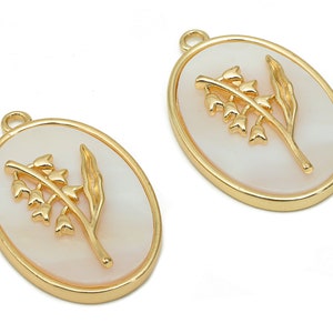 May include: Two gold oval-shaped charms with a white background and a gold lily of the valley design.