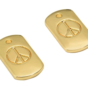 May include: Two gold-colored metal tags with a peace sign design. The tags have a hole at the top for attaching to a chain or cord.