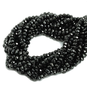 Peut inclure: Un brin de perles de verre facettées noires. Les perles sont petites et rondes, et elles sont enfilées sur un fil transparent.