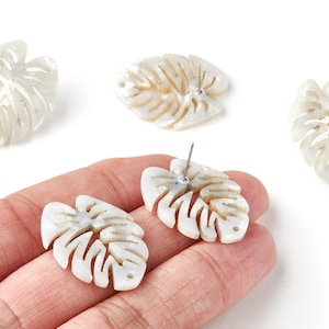 May include: White leaf-shaped earrings with a detailed vein design. The earrings are made of a light-coloured material and have a post backing. The image shows the earrings and two additional leaf-shaped pieces.