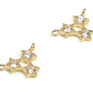 Puede incluir: Encanto de colgante de tono dorado con tres diseños en forma de estrella, cada uno con un strass transparente en el centro.