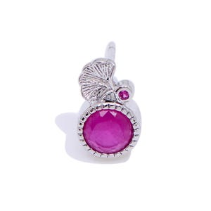 May include: A silver earring with a pink gemstone surrounded by a silver bezel and a silver leaf design.