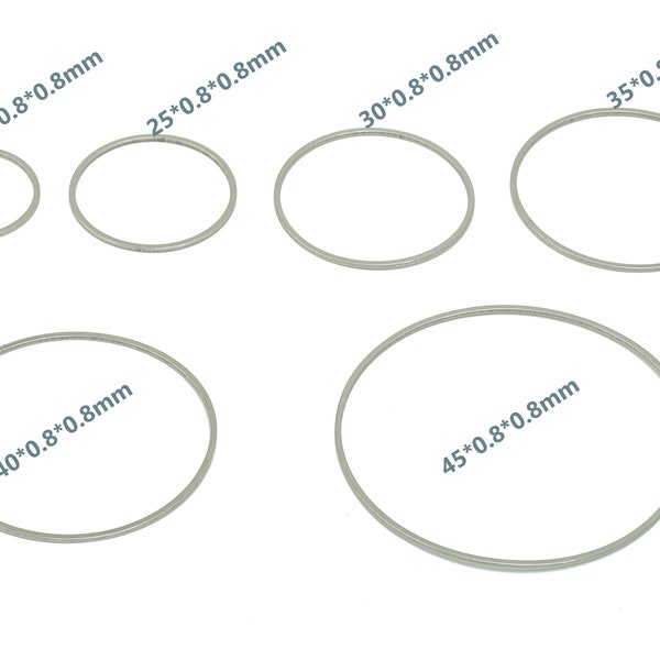 Puede incluir: Seis anillos de metal plateado de diferentes tamaños, con medidas en milímetros impresas en cada anillo. Los anillos están dispuestos en forma de semicírculo sobre un fondo blanco.
