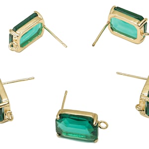 Op de afbeelding: Vier paar gouden oorbelsteunen met rechthoekige, smaragdgroene glazen stenen. Elke oorbel heeft een kleine lus aan de zijkant.