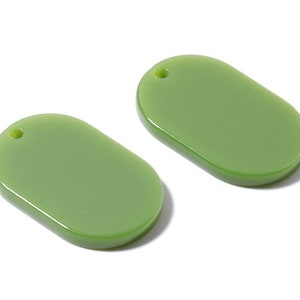 May include: Two green oval-shaped pendant charms with a small hole at the top for stringing.