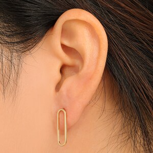 Puede incluir: Un par de pendientes ovalados de oro. Los pendientes son simples y elegantes.