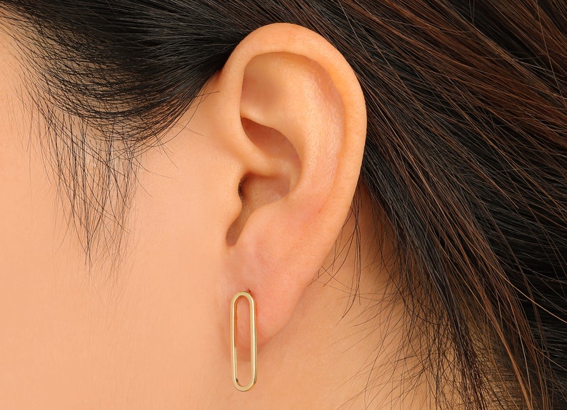 Puede incluir: Un par de pendientes ovalados de oro. Los pendientes son simples y elegantes.