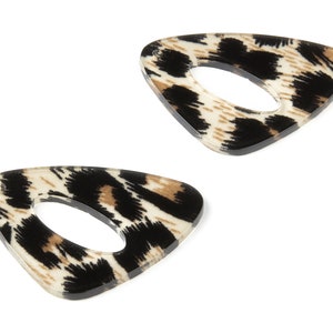 May include: Two triangular hair clips with a leopard print design. The clips have a clear, glossy finish and a central oval opening. The leopard print features black, brown, and cream colours.