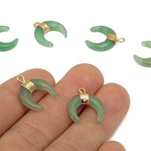 May include: Green crescent moon-shaped pendants with gold-colored accents. The pendants have a loop at the top for attaching to jewelry. The pendants are made of a translucent green material.