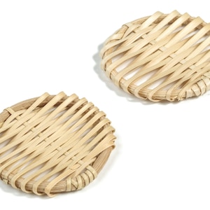 Puede incluir: Dos posavasos redondos de bambú tejido de color marrón claro natural.