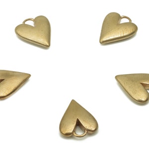 May include: Five gold heart-shaped charms with a loop at the top. The charms are arranged in a circle on a white background.