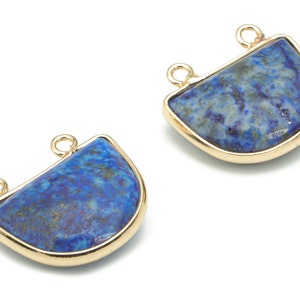 Può includere: Due ciondoli pendenti in metallo dorato con una pietra di lapislazzuli blu a forma di semicerchio. Ogni ciondolo ha due anelli per attaccarlo a una collana o un braccialetto.