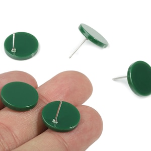 May include: A collection of dark green, round stud earrings. The earrings have a flat, circular design with a silver post. Several earrings are visible, some with the post showing, others with the post hidden.