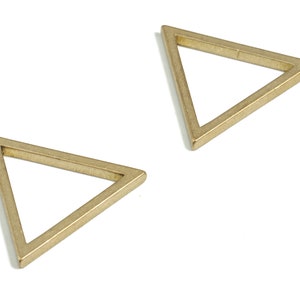 May include: Two gold-colored metal triangle shapes. The triangles are hollow and have a simple, geometric design.