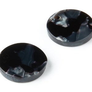 Op de afbeelding: Twee ronde, zwart-wit gemarmerde plastic knoppen met een gat in het midden.