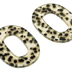 May include: Two oval-shaped, beige and black patterned plastic hair clips.