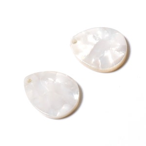May include: Two white pearlescent shell pendant charms with a hole for stringing. The charms are in the shape of a teardrop.