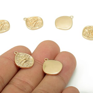 Può includere: Ciondoli in metallo color oro, alcuni con un design ad albero e altri lisci. Ogni ciondolo ha un piccolo anello per il fissaggio ai gioielli. I ciondoli ad albero hanno uno sfondo strutturato.