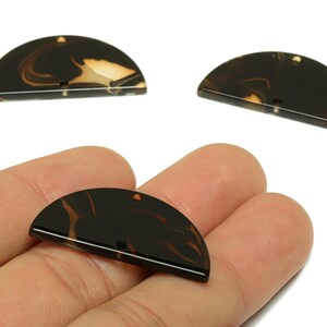 May include: Three half-circle pendants with a marbled brown and tan pattern. One is held in a hand, the others are displayed above. Each pendant has a small hole for stringing. Ideal for jewellery making.