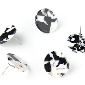 Könnte beinhalten: Vier Paar runde Ohrstecker aus schwarzem und weißem Marmor. Jeder Ohrstecker hat einen silbernen Stift.