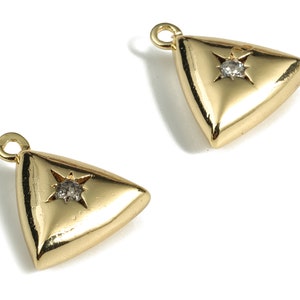 Puede incluir: Dos abalorios dorados en forma de triángulo con un pequeño cristal transparente en el centro de cada uno. Los abalorios tienen un bucle en la parte superior para sujetarlos a un collar o pulsera.