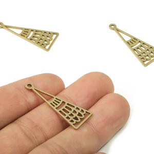 May include: Three brass-colored, openwork pendant charms in a triangular fan shape. The charms have a small loop at the top for stringing and a decorative pattern within the fan. One charm is held in a hand.