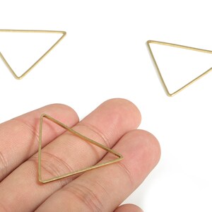 May include: Three gold triangle shaped metal hoops. The hoops are approximately 5 cm in diameter.