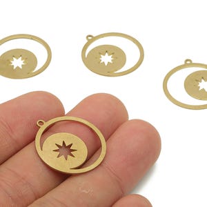 Puede incluir: Colgantes de metal dorado con diseño de estrella. Cada colgante presenta una estrella dentro de un diseño en espiral, con un pequeño lazo en la parte superior para sujetarlo a la joyería. Los colgantes se muestran sobre un fondo blanco.